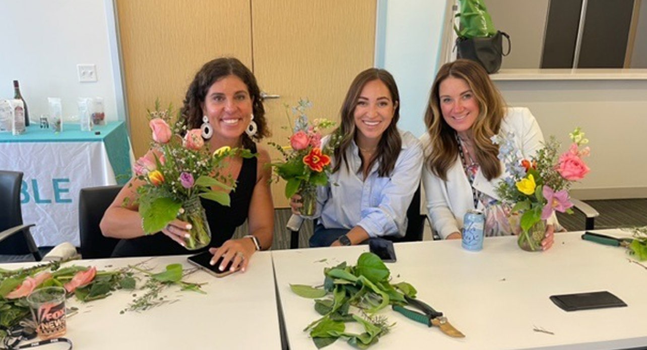 Three FOX employees posing with flower bouquets