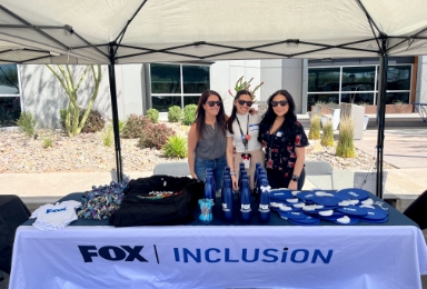 Three FOX employees posing at a FOX Inclusion booth.